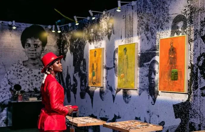 A visitor in a red suit and hat looking at paintings at an art exhibition
